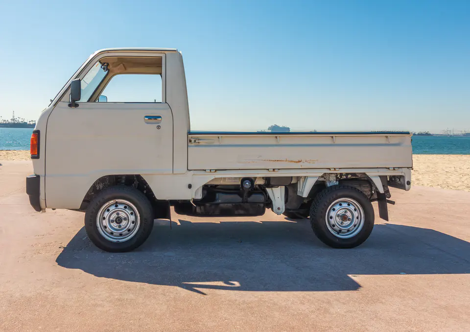 Side view of a white Honda Acty Kei Truck with a drop-side flat bed