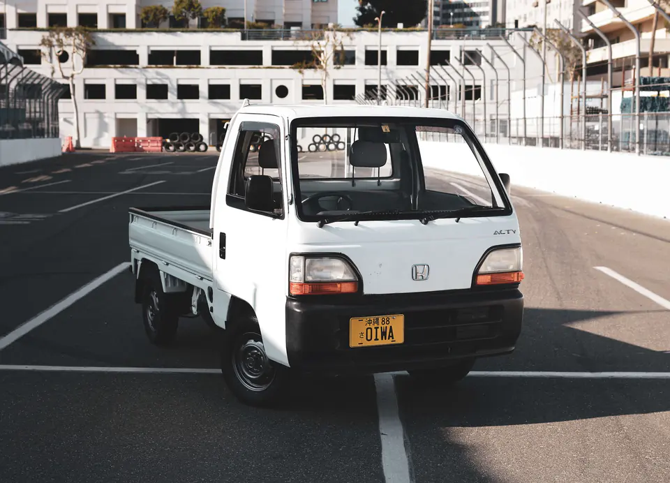 White Honda Acty Kei Truck with a yellow Kei plate parked on a street race circuit