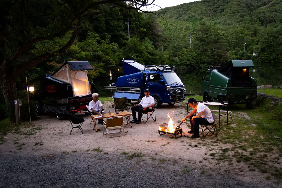 Kei Truck and Kei Van campers parked around a campfire at night