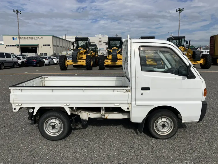 Suzuki Carry Kei Truck at a Japanese vehicle port next to heavy equipment