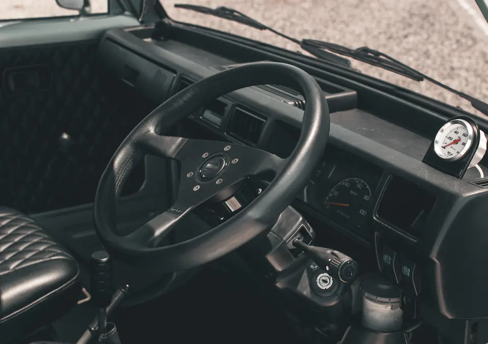 Diamond-stitched black seat covers and an aftermarket steering wheel in a vintage Honda Acty