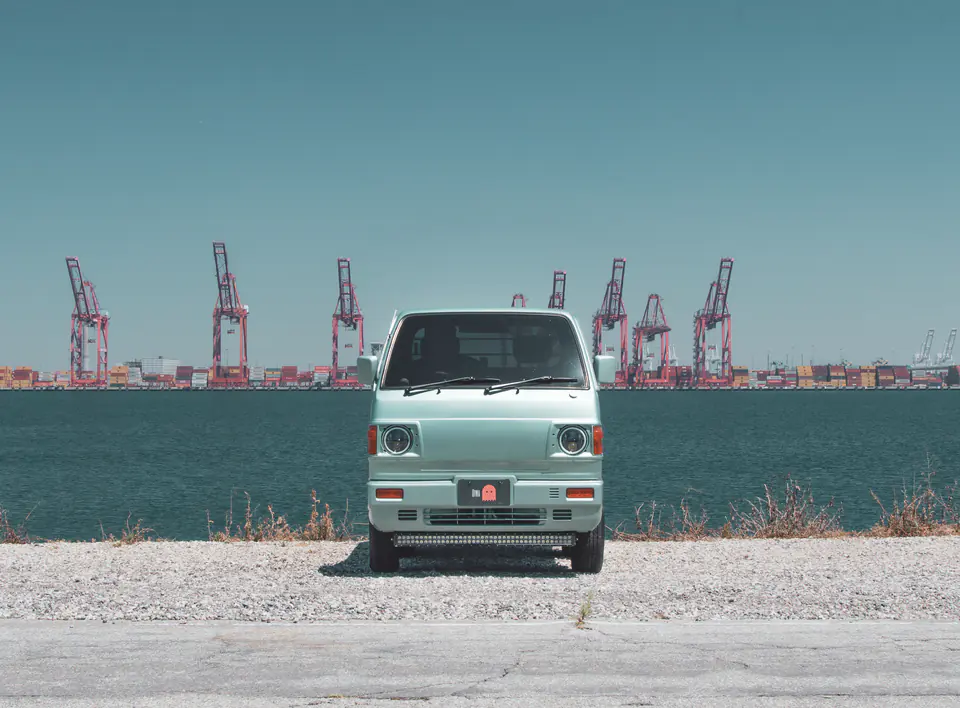 Front view of a mint green vintage Honda Acty with LED halo headlights at the waterfront