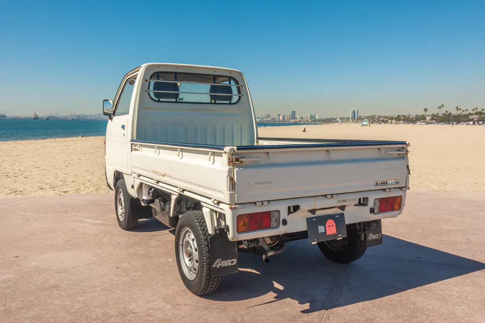Rear three-quarter view of a white Honda Acty Kei Truck with the Long Beach skyline behind it